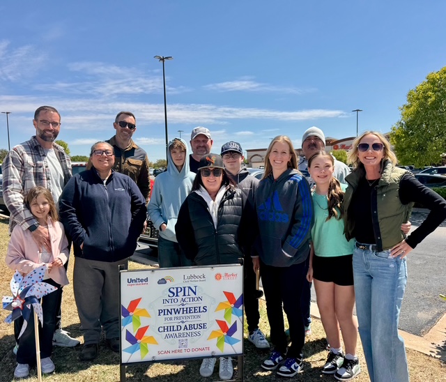 Large group of volunteers gathered behind a Spin Into Action Pinwheels for Prevention sign