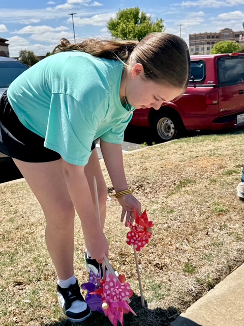 A girl planting red and pink pinwheels in the grass